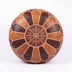 Top view of a two-tone brown leather pouf with alternating panels and central star embroidery