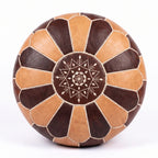 Top view of a tan and dark brown leather pouf with white star embroidery