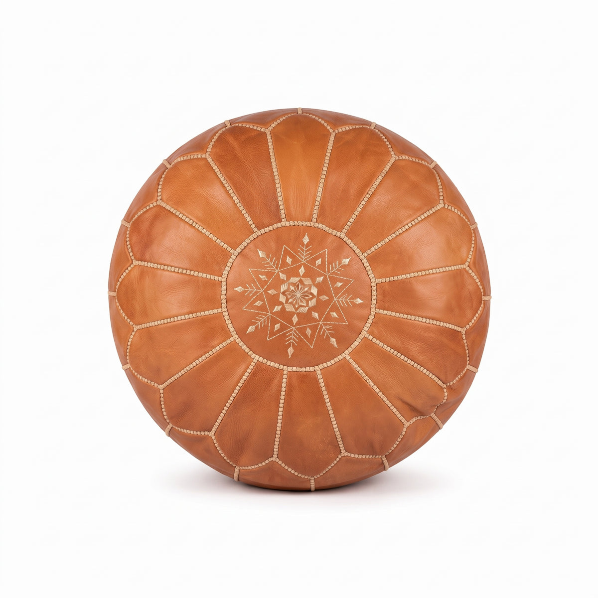 Top view of a caramel tan leather pouf with white stitching and a central embroidered medallion