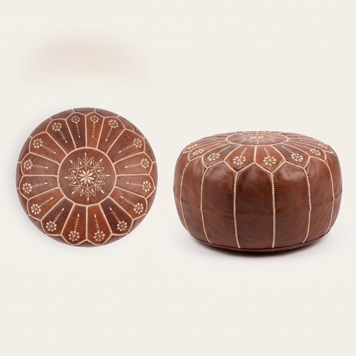 Top and side views of a brown leather pouf with white floral embroidery