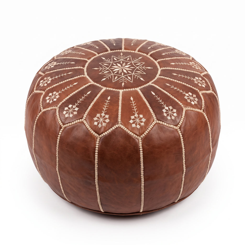 Brown Moroccan leather pouf with scalloped floral embroidery on a white background