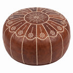 Angled view of a brown leather pouf showing its embroidered floral top