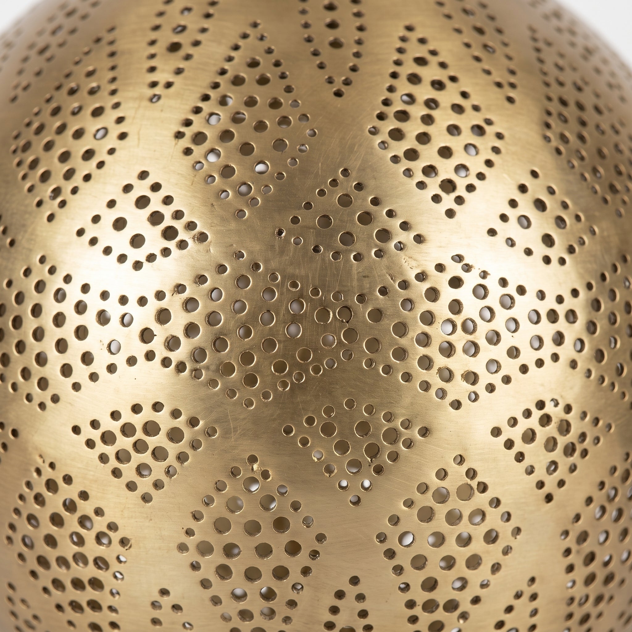 Close-up of the geometric perforations in the brass lamp shade