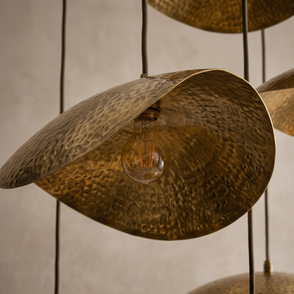 Close-up of a curved hammered brass chandelier shade and bulb