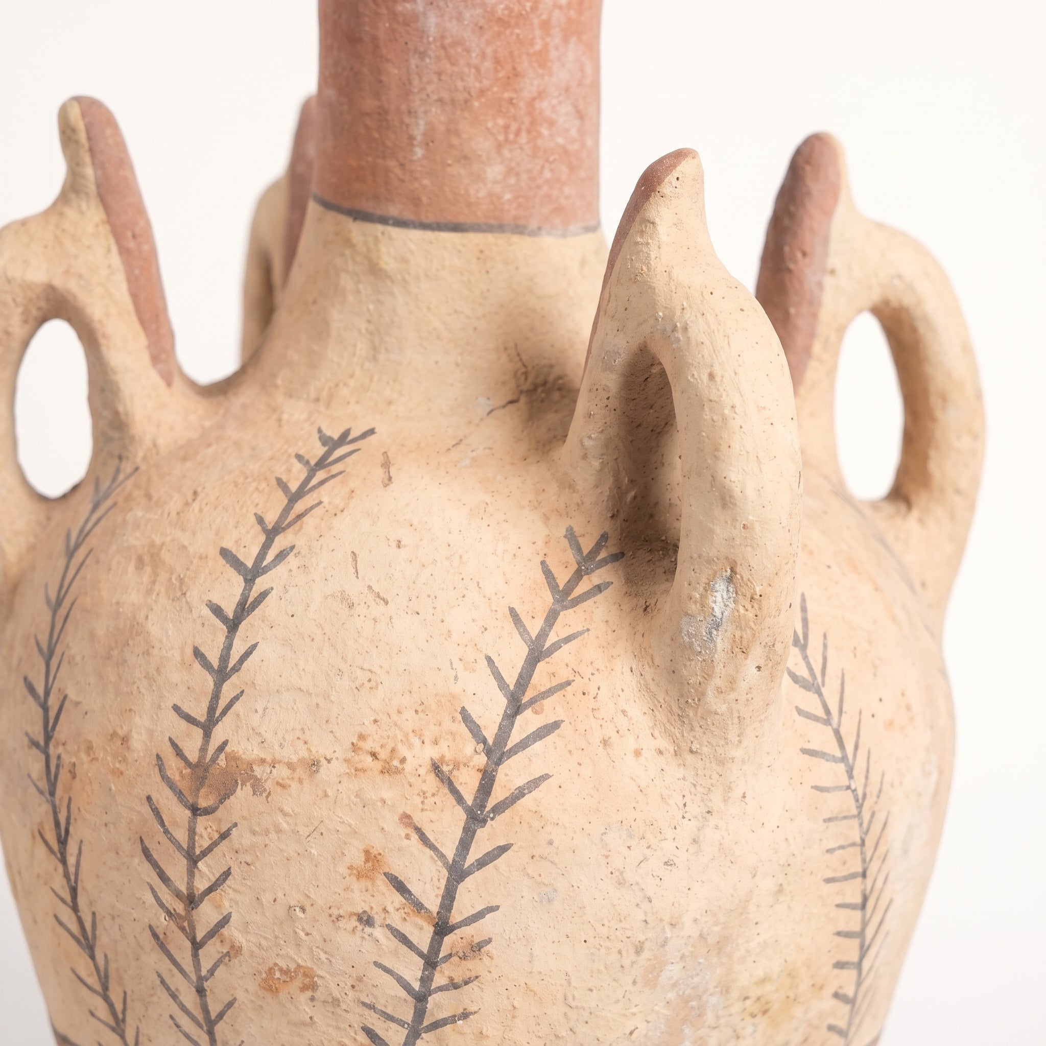 Close-up of the sculpted handles and botanical decoration on the ceramic vase