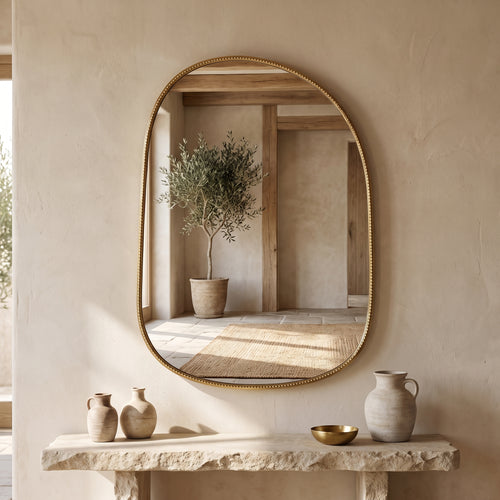 Hand-etched brass mirror displayed above a console in a neutral interior