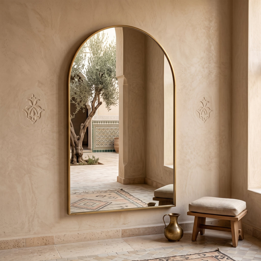 One arched brass wall mirror from the set installed in a warm Moroccan interior