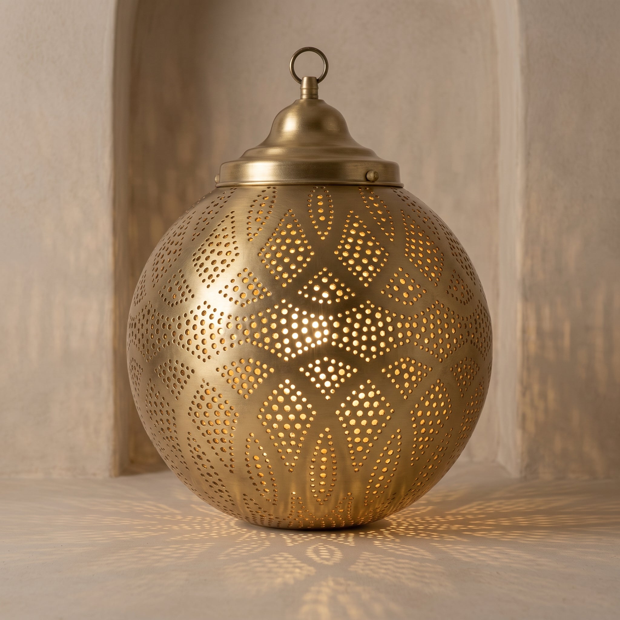 Bronze-finish pendant light illuminating a tabletop with pierced patterns