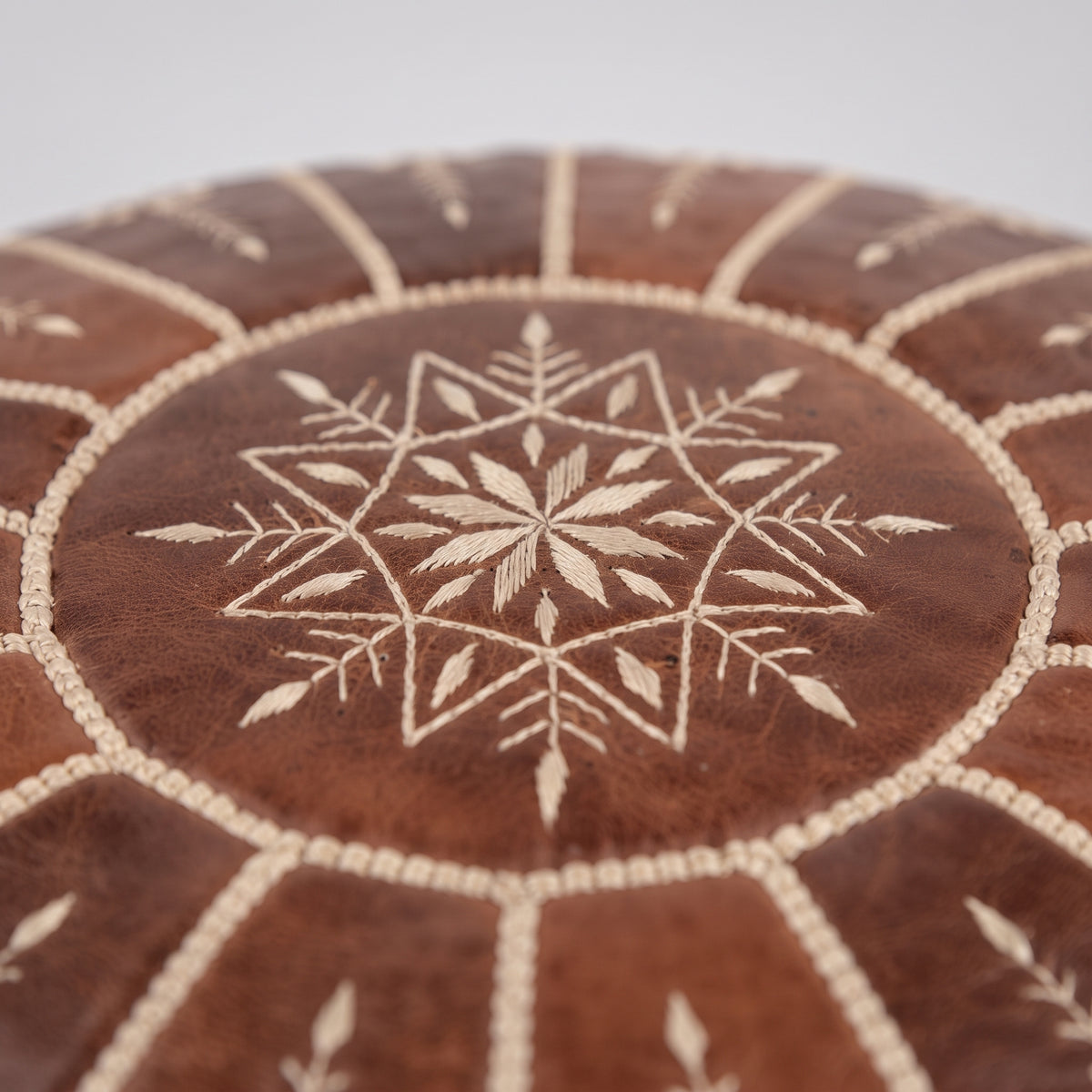 Detail of the stitched star motif on a brown Moroccan leather pouf