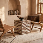 Chevron wood-inlay cube table with a tea set between woven wooden chairs