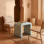 Turquoise and cream arch table with striped sides beside cushioned wooden chairs