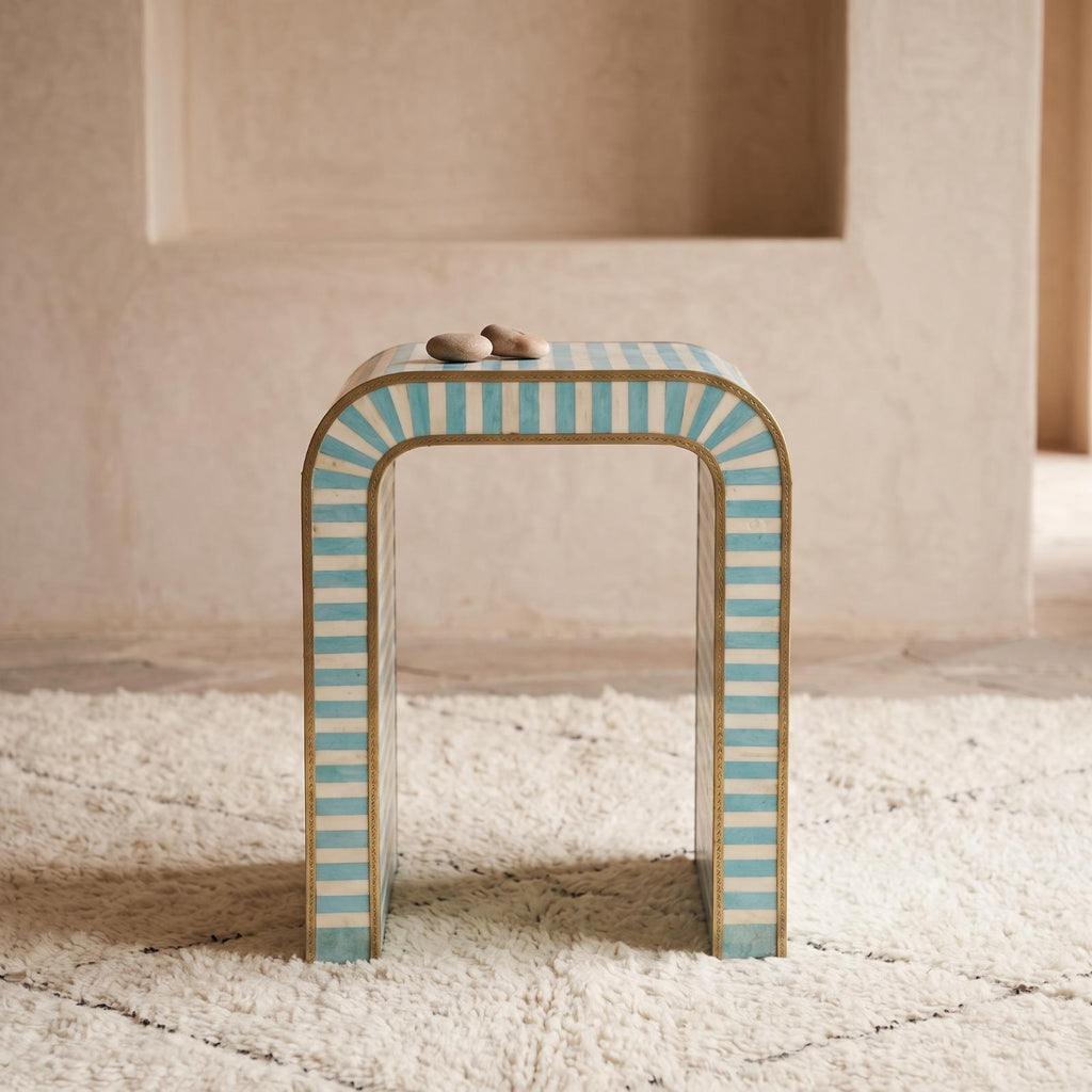 Front view of a turquoise and cream striped arch table topped with small cups