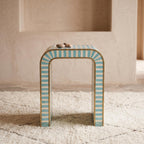 Front view of a turquoise and cream striped arch table topped with small cups
