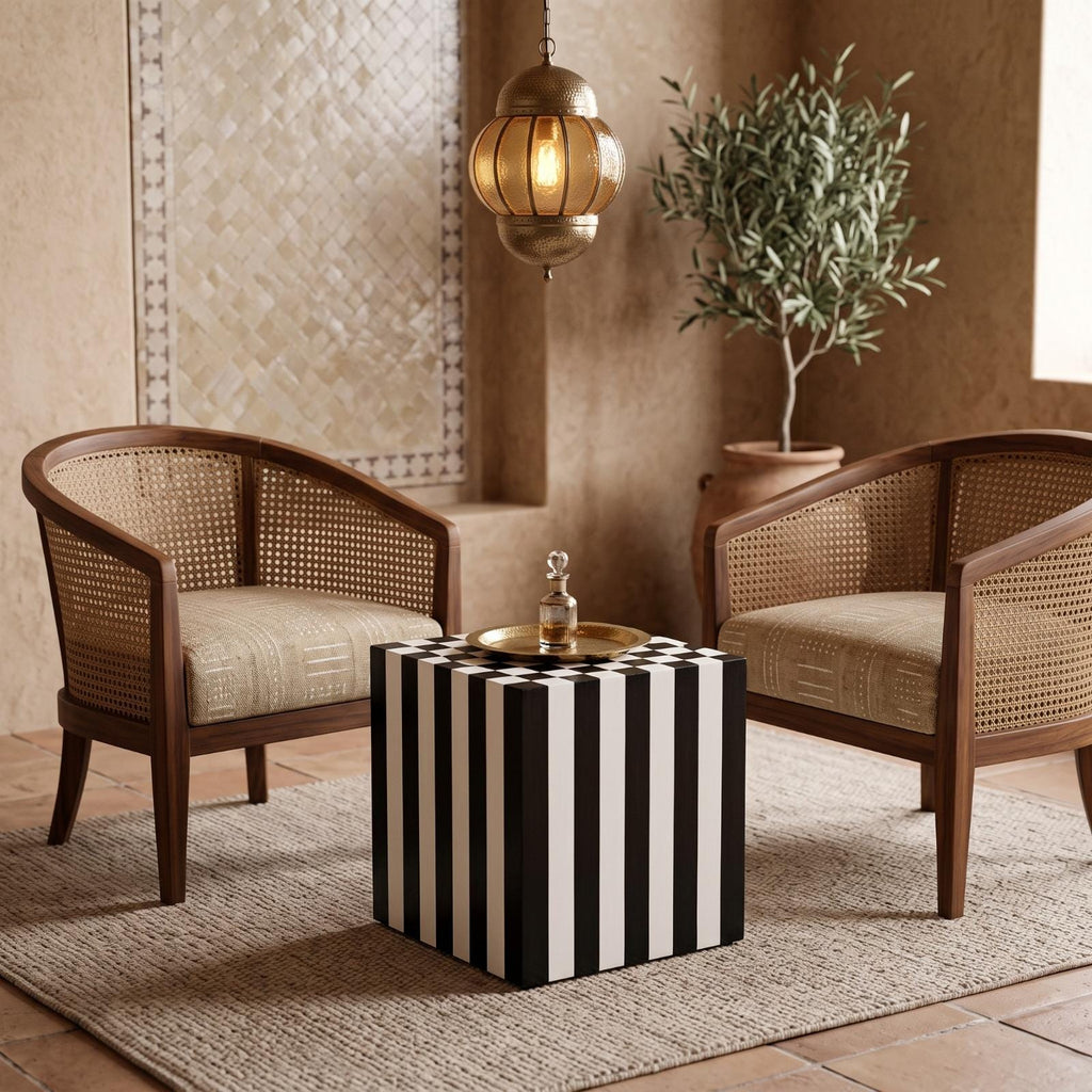 Black and white striped cube side table with a tea tray between two cane armchairs