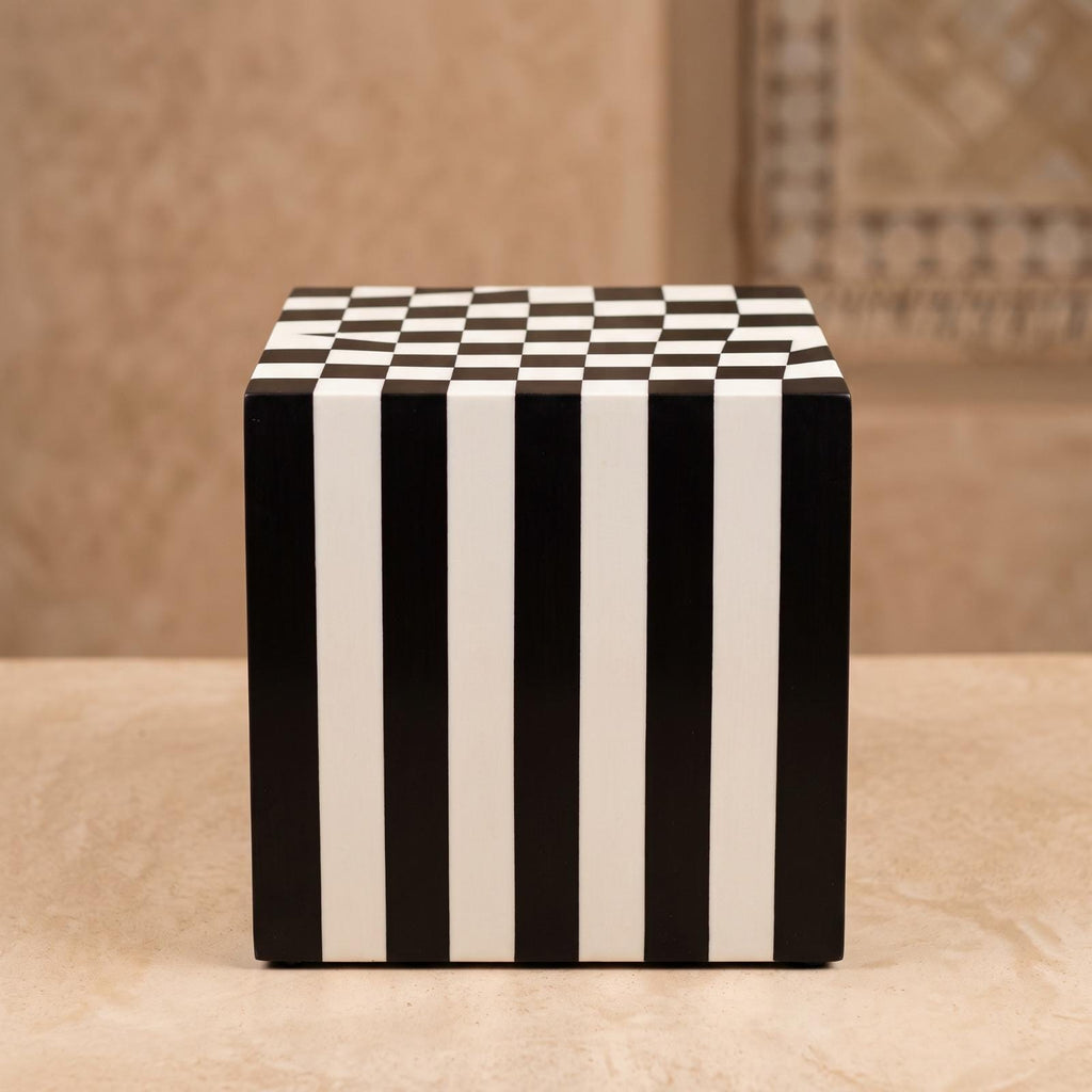Black and white cube table with vertical striped sides and a checkerboard top