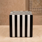 Black and white cube table with vertical striped sides and a checkerboard top