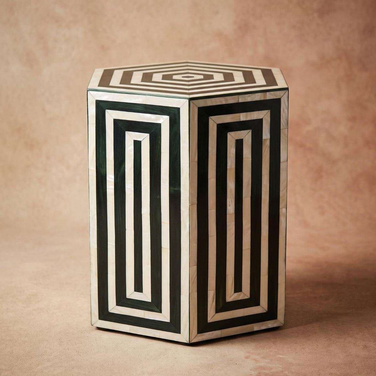 Dark green and cream hexagonal side table with geometric borders against a beige wall
