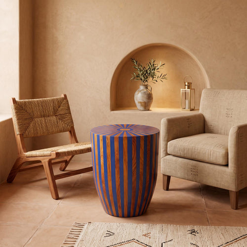 Blue and orange striped wooden drum table between two chairs beneath an arched wall niche