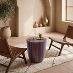 Blue and orange wood-inlay drum table between cushioned chairs near a bright window