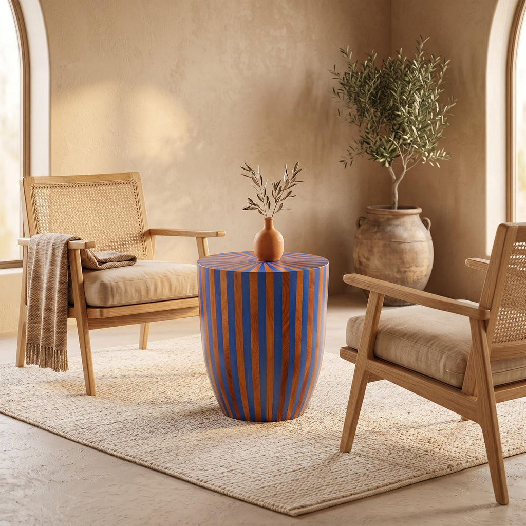 Blue and orange striped drum table topped with a vase between two wooden armchairs