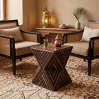 Dark chevron-inlaid hourglass table with a tea set in a seating area with a Moroccan rug