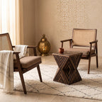 Dark geometric hourglass table between two wooden armchairs in a beige interior