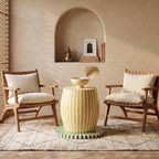 Yellow striped drum side table topped with a bowl between two cushioned chairs