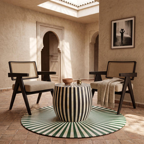 Black and cream striped drum table on a radial green rug between two wooden armchairs