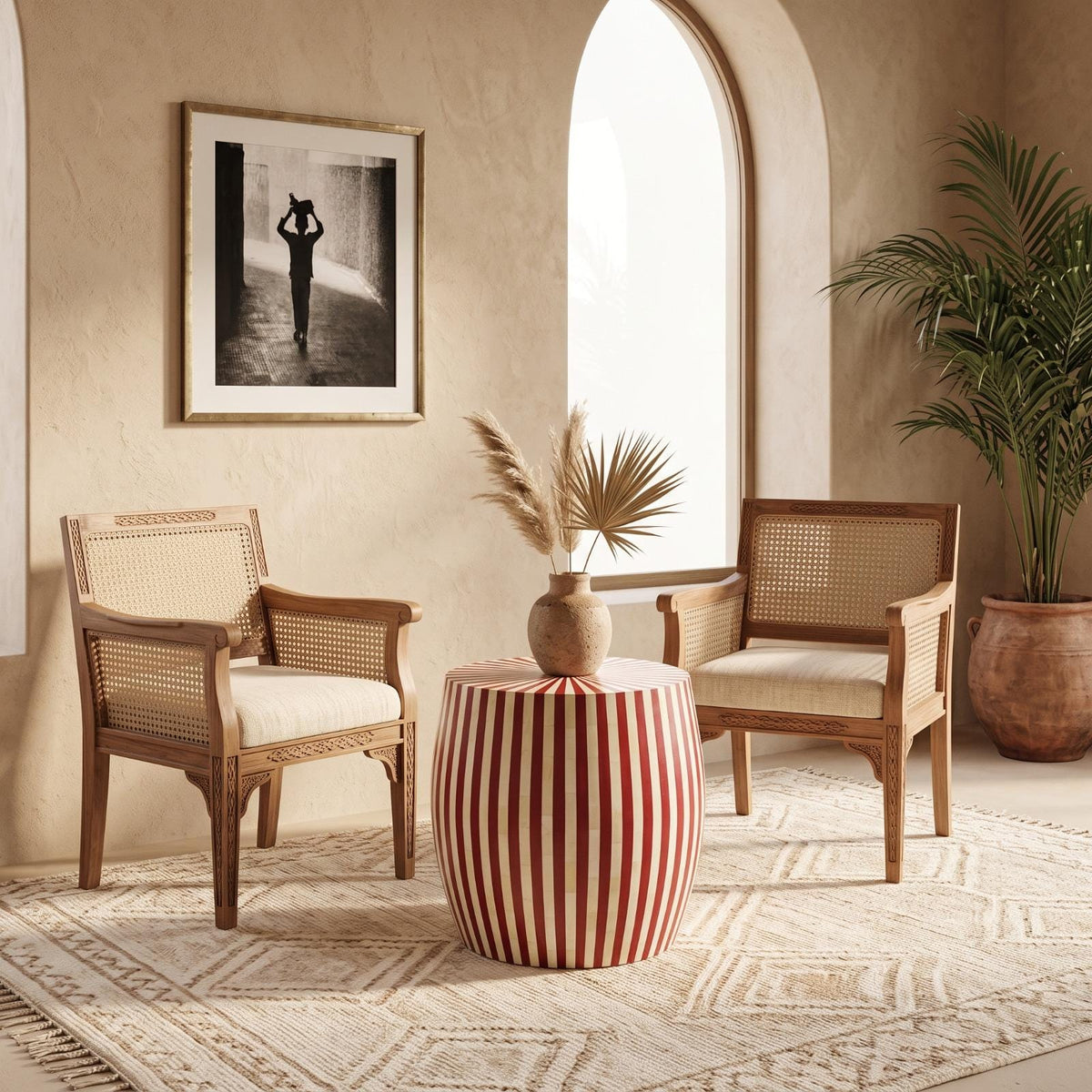 Red and cream striped drum side table between cushioned chairs beside an arched window