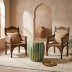 Green and natural wood striped drum side table between two cushioned wooden armchairs