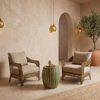 Green striped drum side table between armchairs in a beige room with an arched doorway