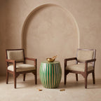 Green striped wooden side table with a sunburst top between two woven wooden chairs
