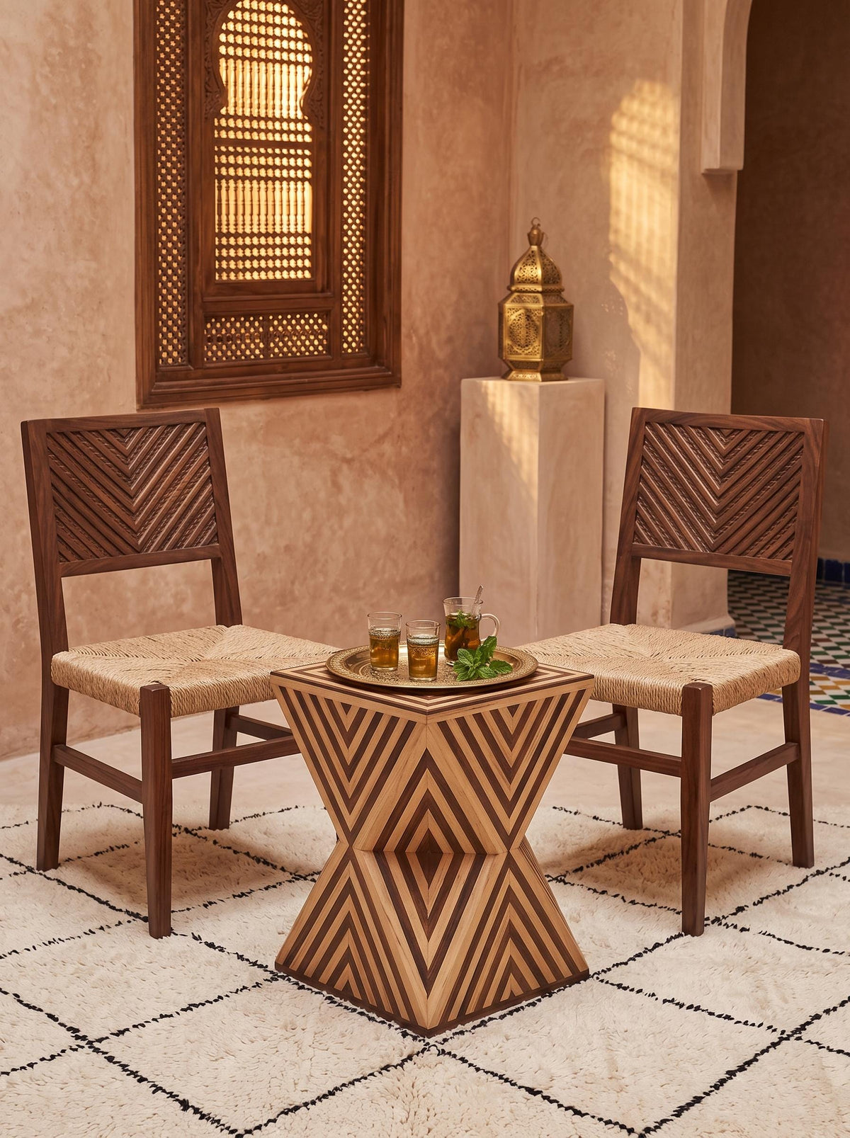 Geometric wooden hourglass table with light and dark stripes between two woven-seat chairs