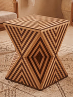 Angled view of a wooden hourglass side table showing its striped square top and tapered center