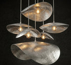 Silver finish hammered petal pendant lights with warm bulbs in a multi-pendant arrangement