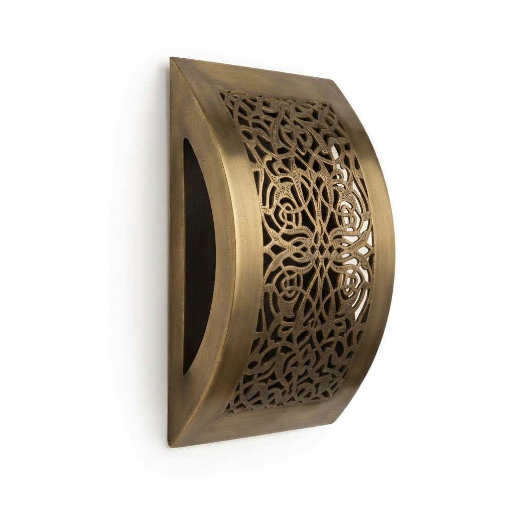 Side view of a curved brass wall sconce with floral lattice and an open crescent-shaped edge