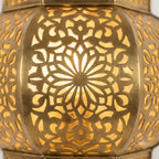 Close-up of illuminated floral cutouts on a Moroccan brass globe lantern wall sconce