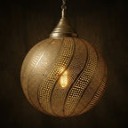 Close-up of an illuminated brass globe pendant with curved spiral perforations
