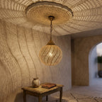 Spiral Bands brass globe pendant above a wood table in a neutral interior