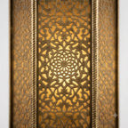 Close-up of illuminated floral lattice on an ornate brass tower wall lantern
