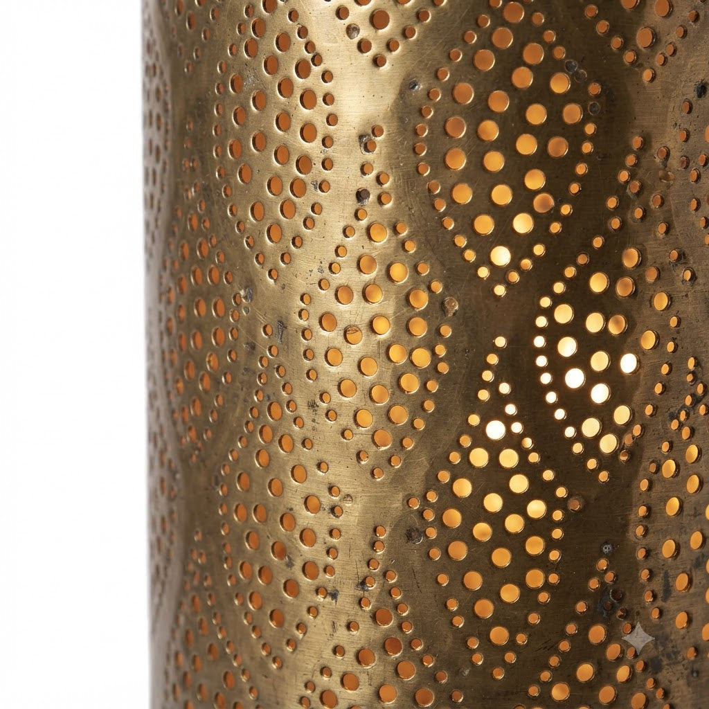 Close-up of teardrop-shaped perforated motifs on a brass wall sconce