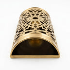 Moroccan brass wall sconce laid on its side, showing pierced starburst patterns and an open end