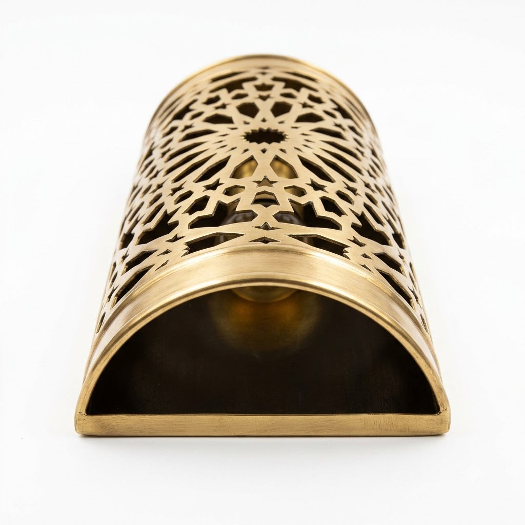 Moroccan brass wall sconce laid on its side, showing pierced starburst patterns and an open end