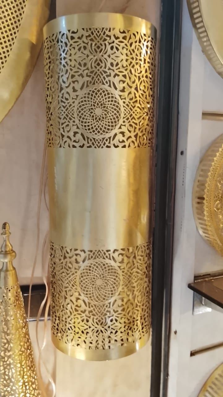 Twin rosette brass wall sconce with a smooth central band, displayed vertically in a workshop