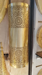 Twin rosette brass wall sconce with a smooth central band, displayed vertically in a workshop
