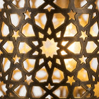 Close-up of illuminated star-shaped lattice cutouts in a Moroccan brass wall sconce
