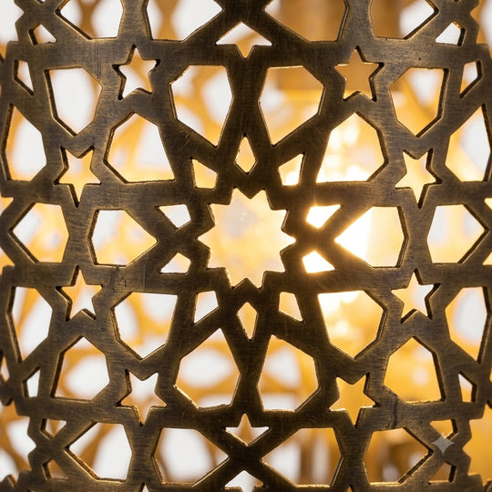 Close-up of illuminated star-shaped lattice cutouts in a Moroccan brass wall sconce