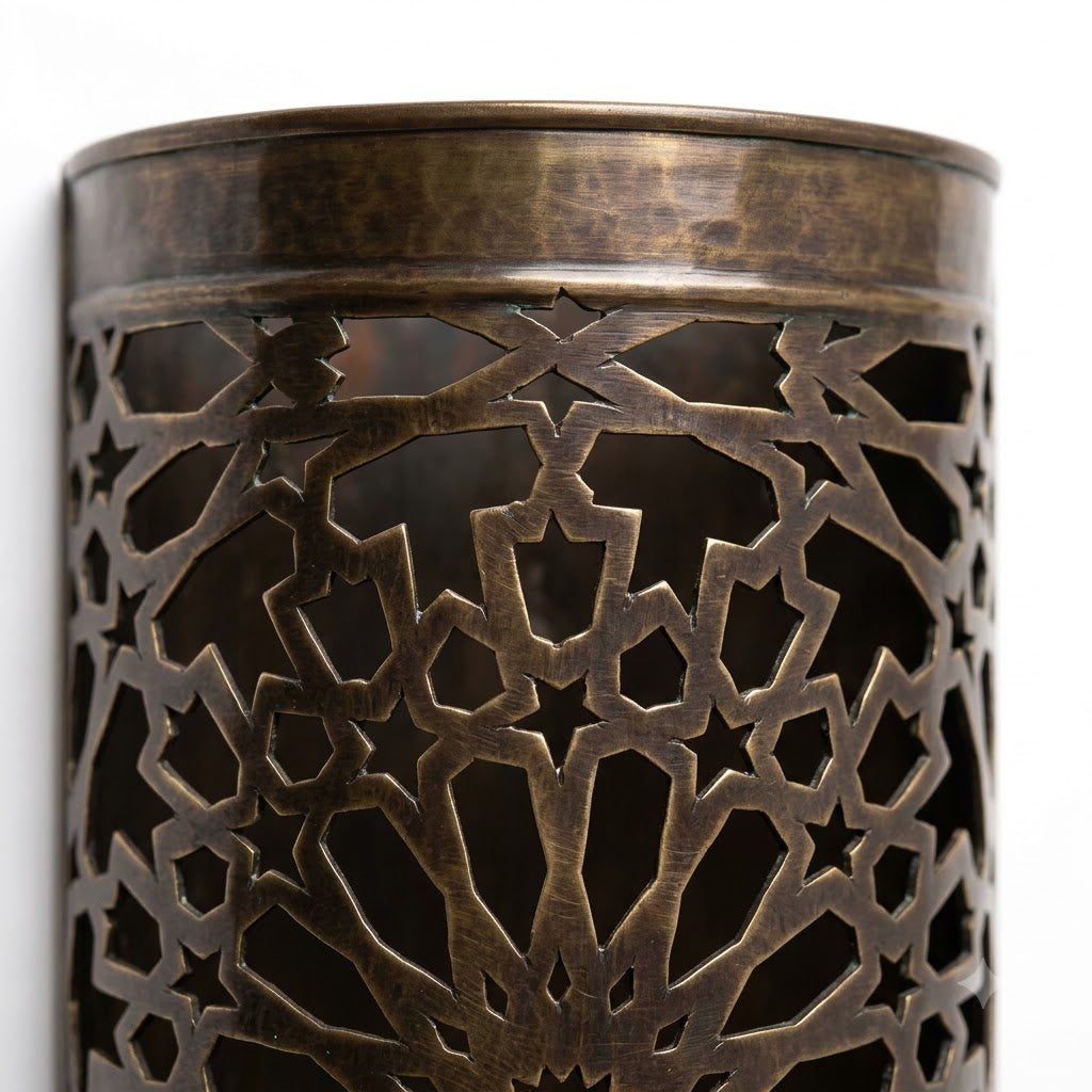 Close-up of the top rim and pierced starburst pattern of a dark brass wall sconce