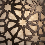 Close-up of large star-shaped cutouts on a dark brass lattice wall sconce