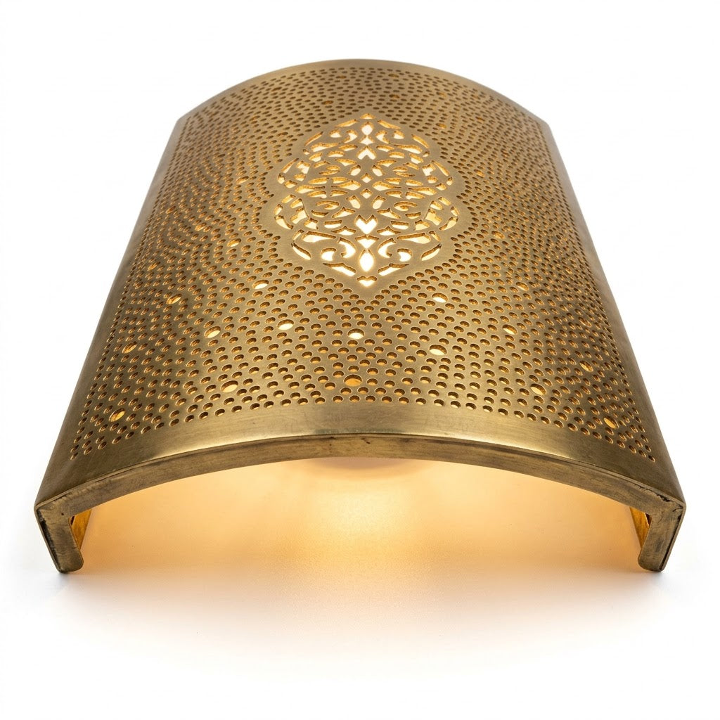 Angled view of a curved brass wall sconce with a central arabesque medallion